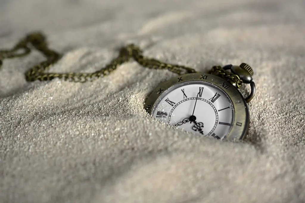 Vintage pocket watch in sand representing opening hours and timing for visiting Selong Belanak Beach in Lombok