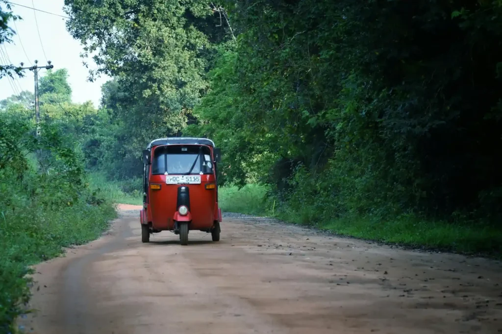 Traditional tuk tuk driving through tropical road near Hiriketiya Sri Lanka