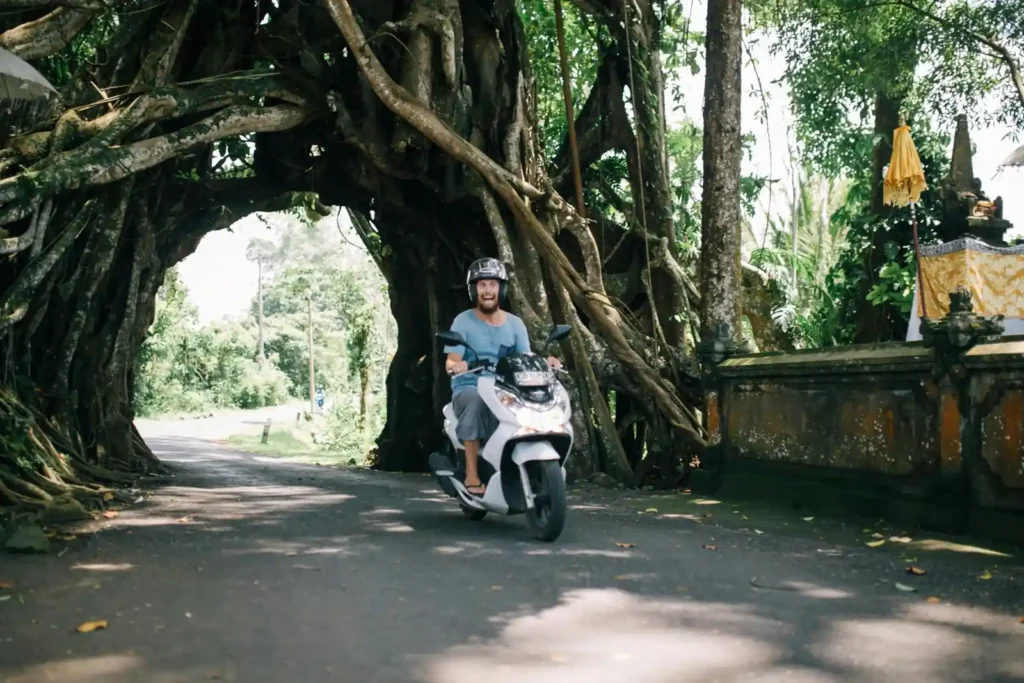 Traveler riding a scooter through tropical Bali roads toward Uluwatu