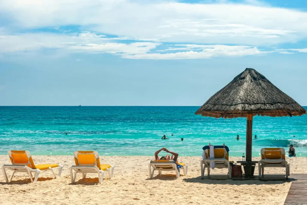 Tropical beach with sun loungers and umbrella overlooking turquoise ocean, ideal for remote work lifestyle