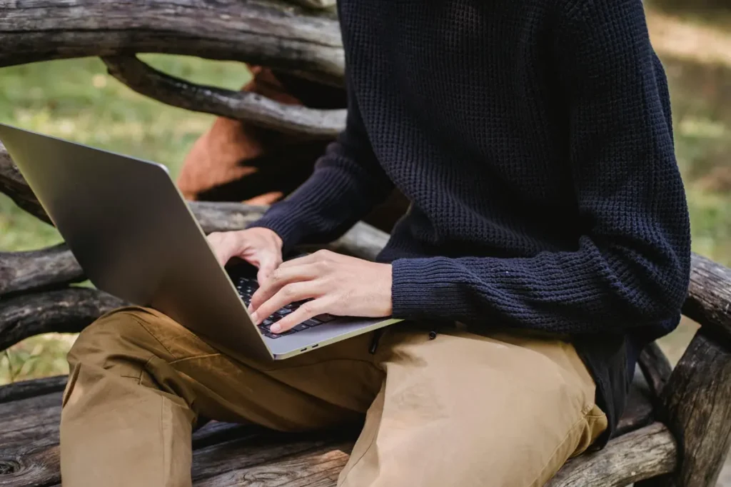 Person working on a laptop outdoors, representing cafes with Wi-Fi for remote work
