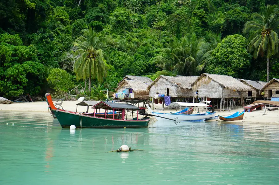 Traditional beach village with wooden huts, fishing boats, and tropical greenery by the sea