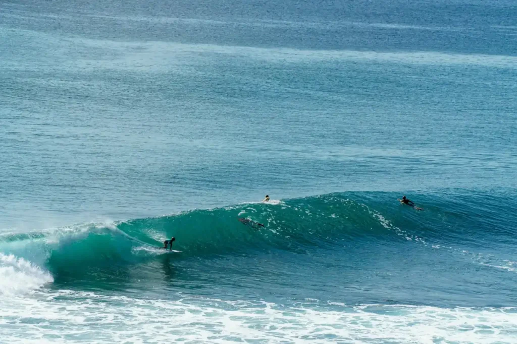 Surfers riding clean turquoise waves at Nyang Nyang Beach Bali.
