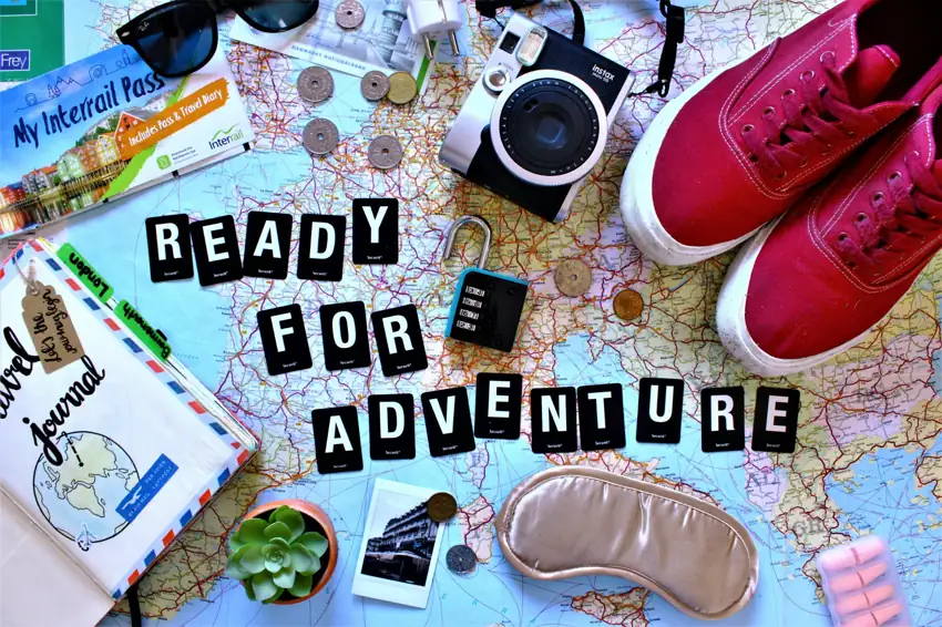 Travel essentials on a map with camera, passport, lock, and items symbolizing safety and travel planning