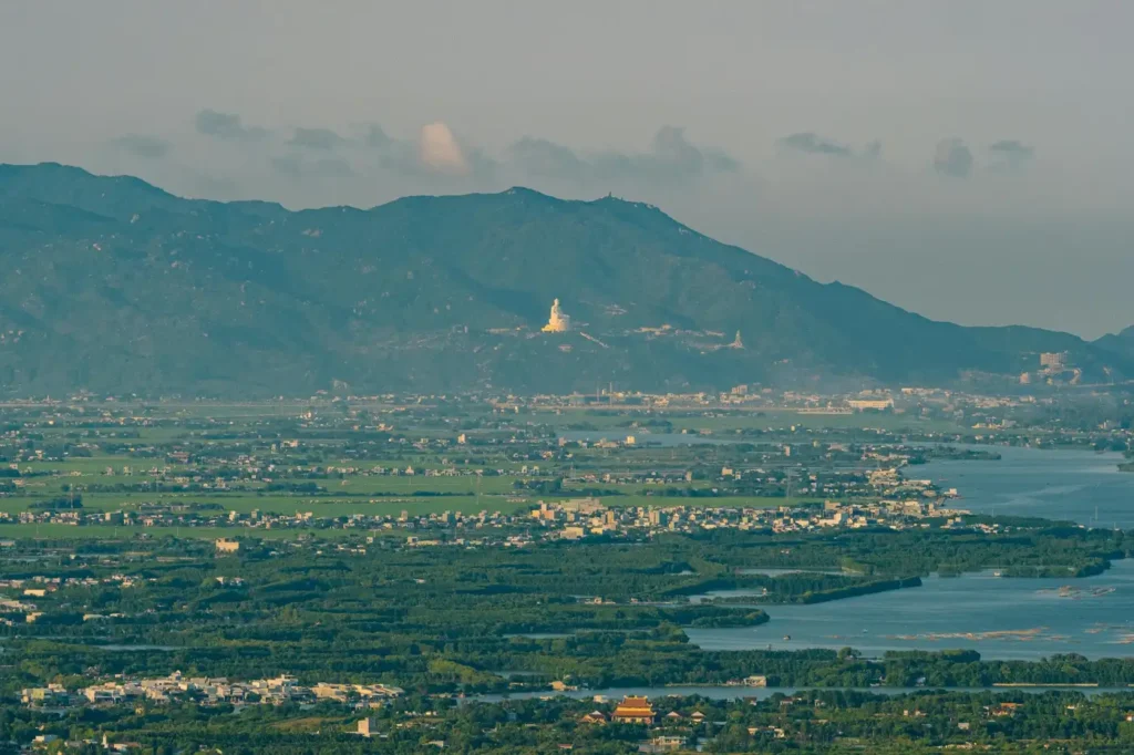 Panoramic view of Ba Dinh Mountain in Vietnam overlooking rivers, green countryside, and distant mountain ranges at sunset.