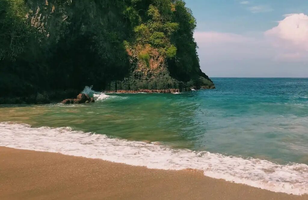 Hidden Bali beach with limestone cliffs and turquoise water near Uluwatu”