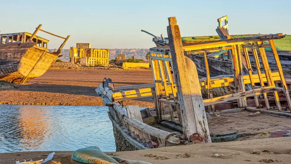 Traditional wooden fishing boats resting near the shore at sunset in Chabahar, Iran, along the scenic Makran Coast.