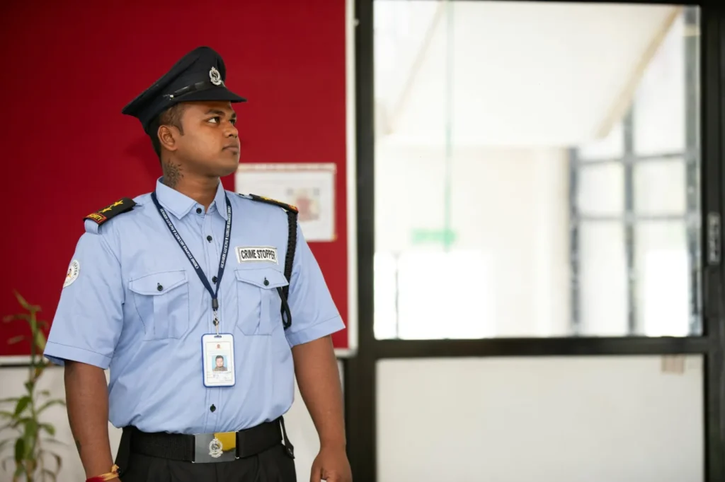 Airport security guard standing near an entrance during the check-in and security process at an airport terminal.