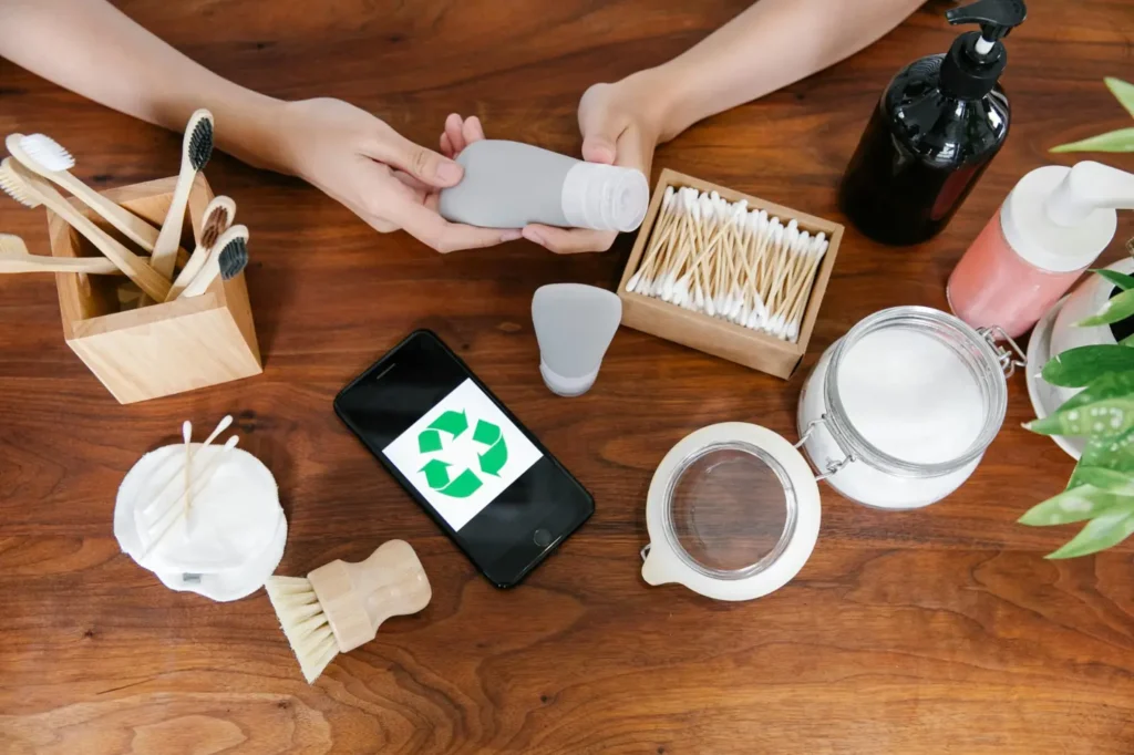 Eco-friendly travel essentials including bamboo toothbrushes, reusable containers, cotton pads, and sustainable skincare products on a wooden table.