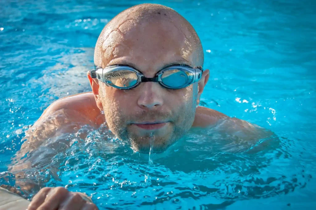 Man swimming in clear blue ocean water wearing goggles at Hiriketiya Beach
