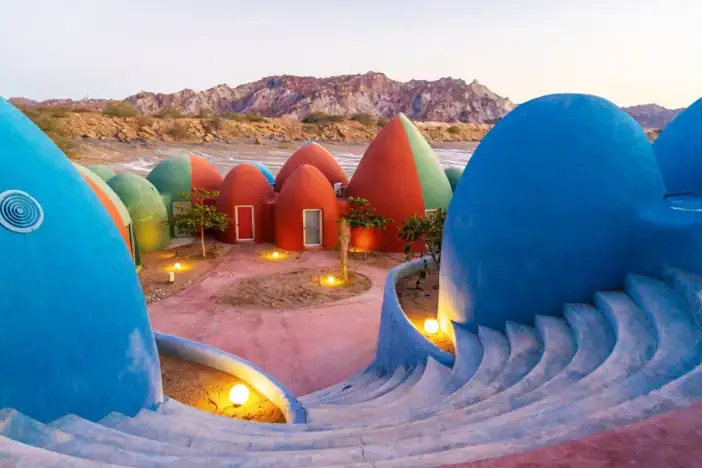 Colorful dome-shaped rooms at Hormuz Beach Hotel surrounded by the rocky landscape of Hormuz Island, Iran.