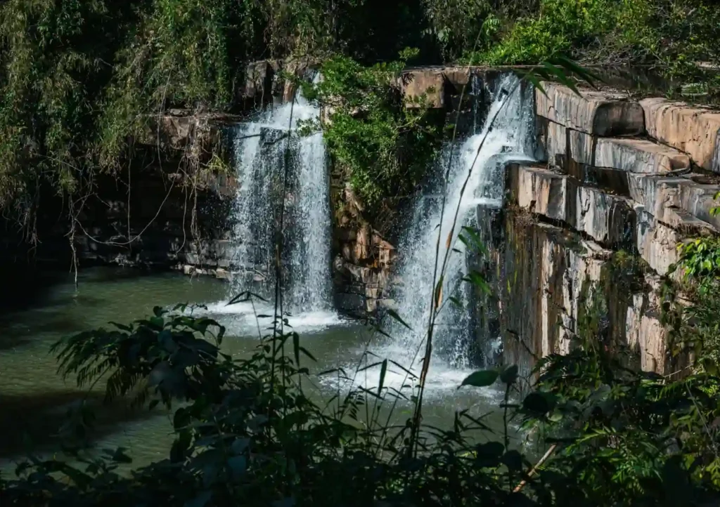Klong Chao Waterfall in Koh Kood surrounded by dense jungle, with clear water cascading into a natural swimming pool below rocky cliffs.