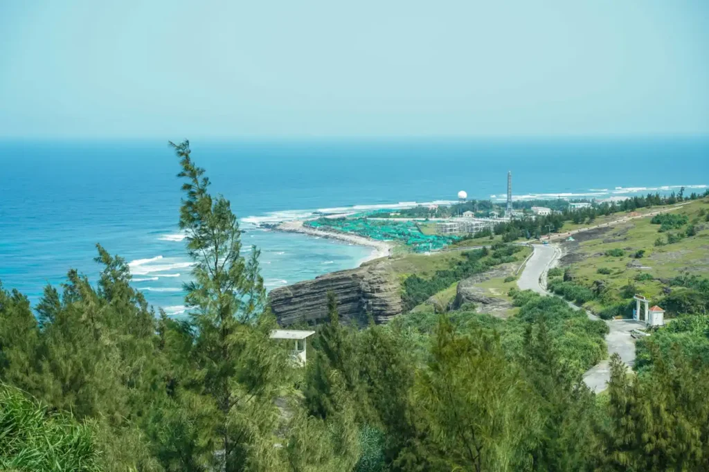 Panoramic coastal landscape of Ly Son Island in Vietnam with volcanic cliffs, winding roads, green hills, and deep blue ocean views.