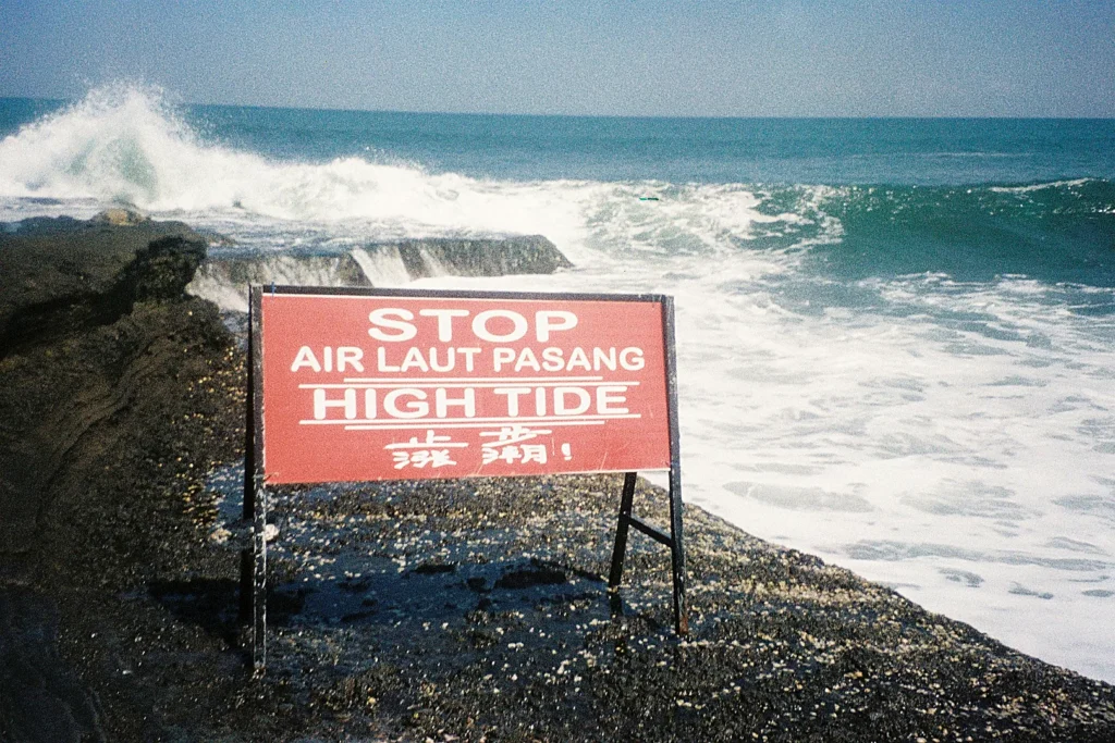 Warning sign near rough ocean waves at a Bali beach with strong currents