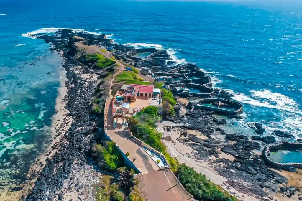 Aerial view of Phu Quy Island in Vietnam with volcanic rocky coastline, turquoise ocean, coastal road, and natural seaside pools.