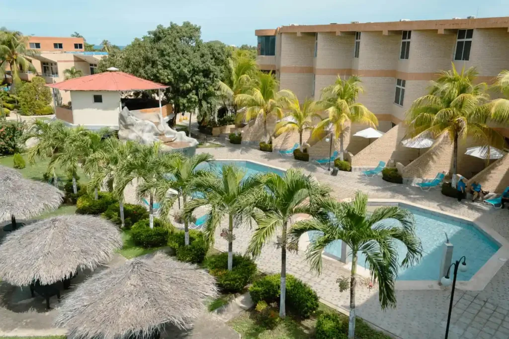 Tropical resort with palm trees, swimming pools, and lounge areas surrounded by modern buildings near the beach in Port Barton.