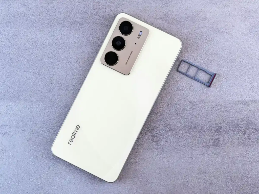 White Realme smartphone with triple camera setup and SIM card tray placed on a textured surface.