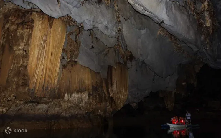 Puerto Princesa Underground River cave featuring towering limestone formations and a boat tour inside the cavern.