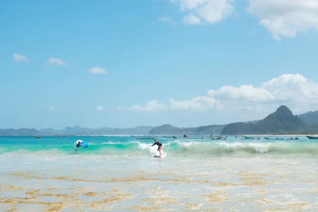 Beginner surfers catching clean waves at Selong Belanak Beach, one of Lombok’s most popular surf spots