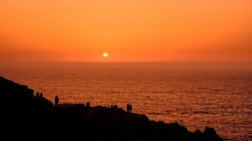 Sunset over the ocean at Balangan Beach with orange skies, calm sea view.