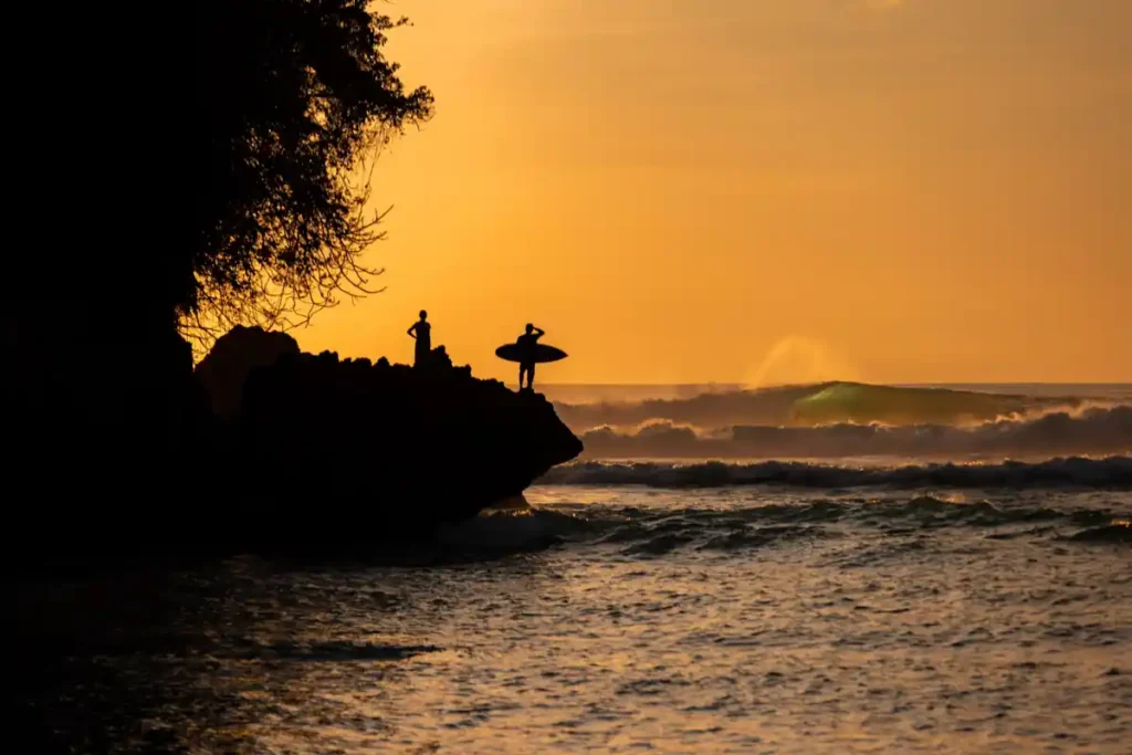 Surfer watching waves at sunset on Balangan Beach, Bali.

