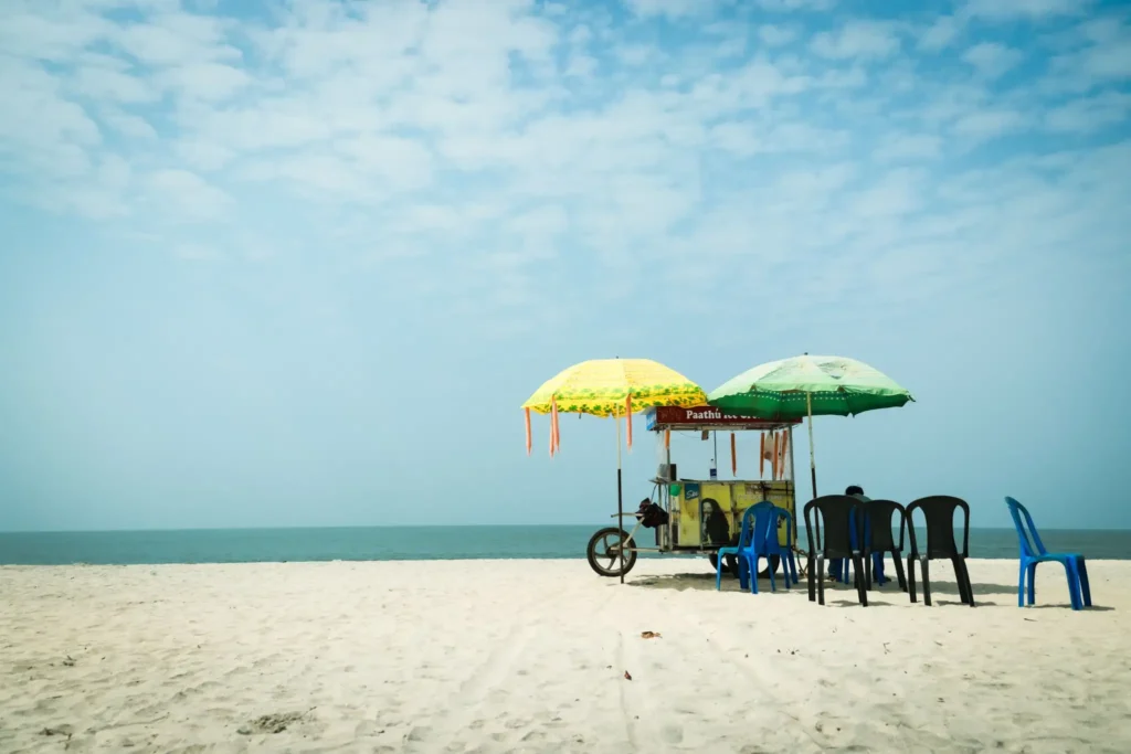 Beach vendor stall with umbrellas on a sandy shore.
