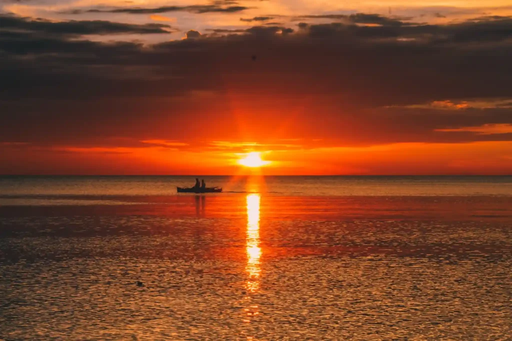 Boat silhouette at a tropical beach sunset.