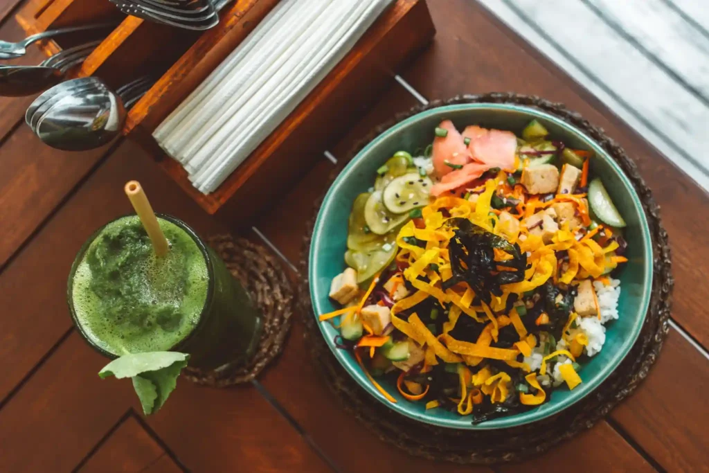 Colorful rice bowl with fresh vegetables and a green smoothie.