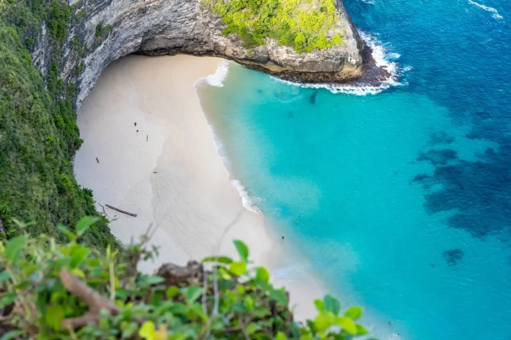 Kelingking Beach viewpoint in Nusa Penida, Bali, featuring turquoise water, white sand, and dramatic limestone cliffs.