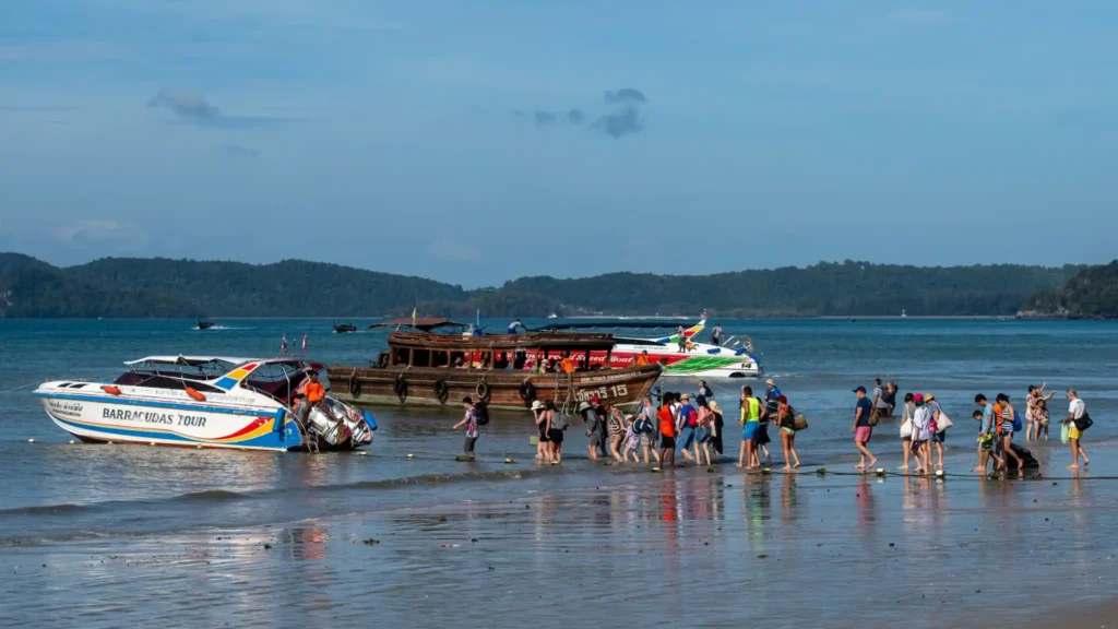 Travelers boarding speedboats and ferries from the shallow beach at Koh Lipe, Thailand. 