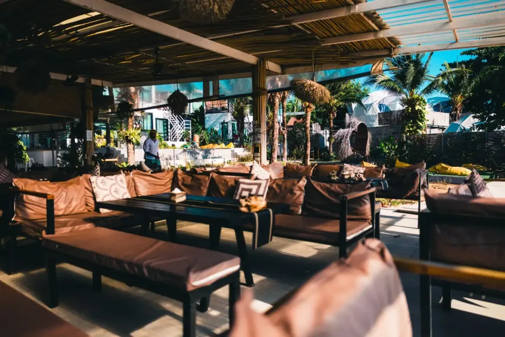 Open-air beach resort lounge with cushioned seating, palm trees, and tropical accommodation in Koh Lipe.