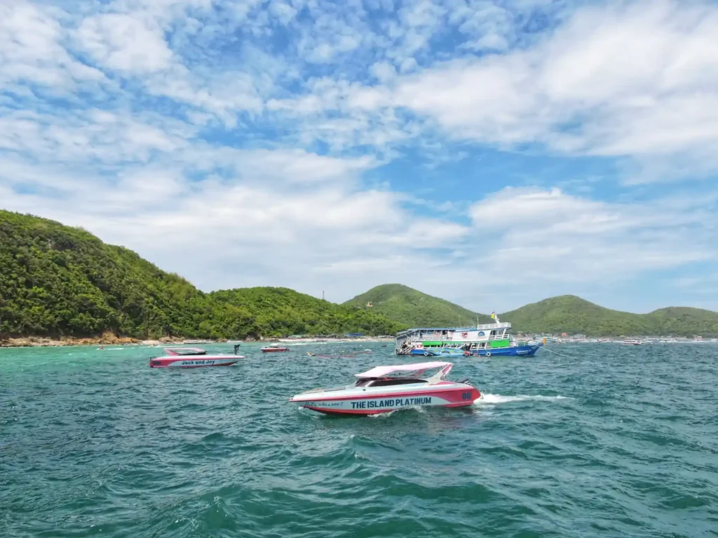 Speedboats and ferries crossing turquoise water near the green hills of Koh Lipe, Thailand.
