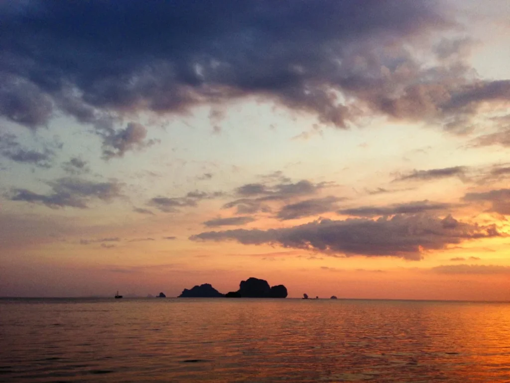 Dramatic sunset over calm sea near Koh Lipe with dark island silhouettes and layered clouds.