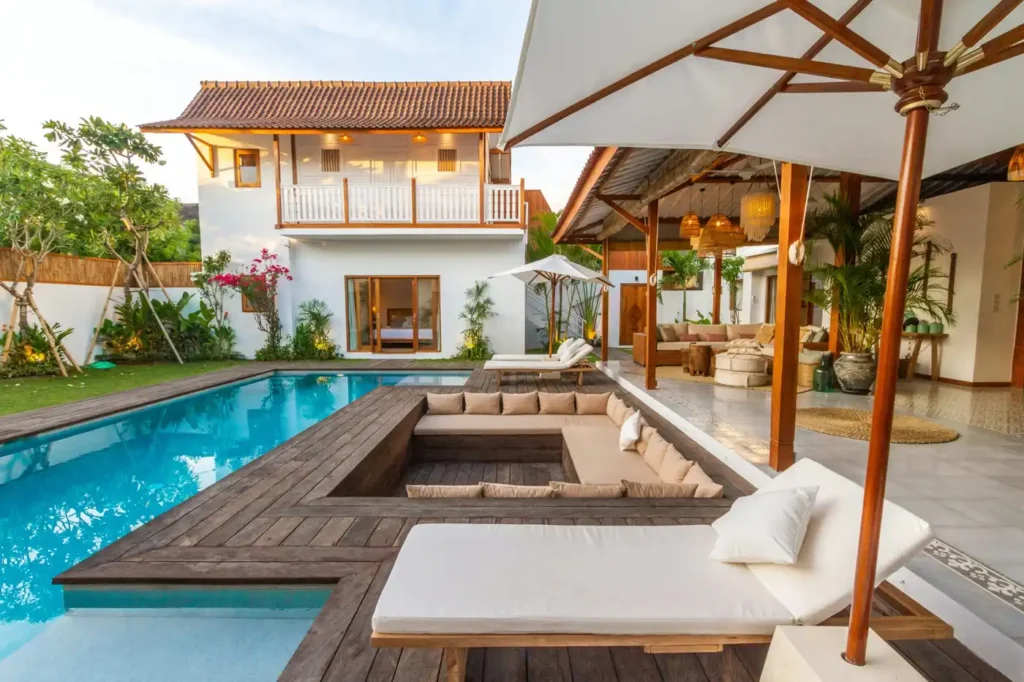 Luxury Selong Belanak villa with private pool, sun loungers, tropical garden, wooden deck, and open-air lounge area.