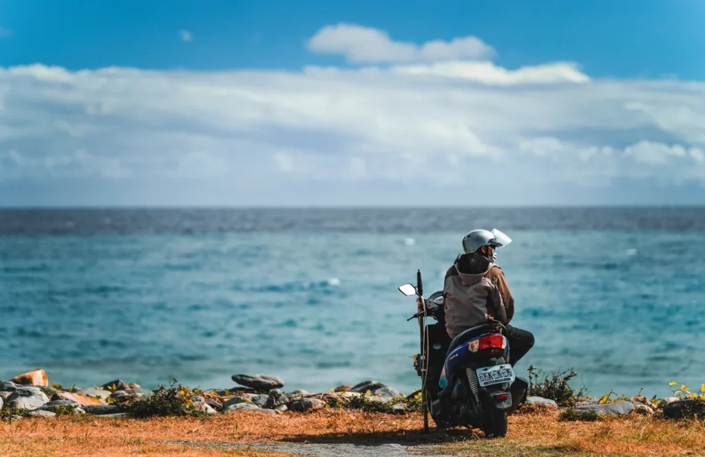Traveller sitting on a motorbike beside the sea, representing scooter travel to Anda Beach in Bohol.