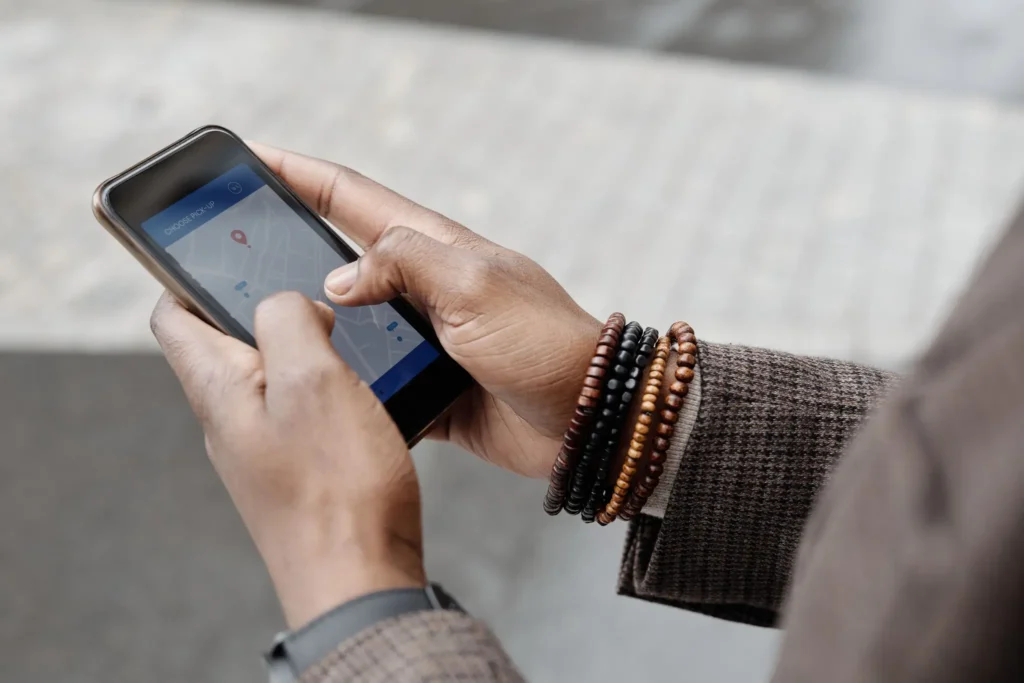 Person using a smartphone navigation app with a digital map and location pin to find directions and travel routes.