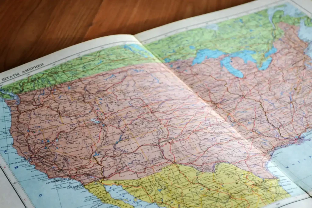 Open travel map on a wooden table showing routes and country details for trip planning. 