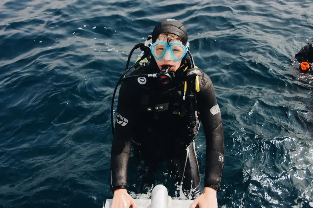 Scuba diver in open ocean water preparing for a dive.