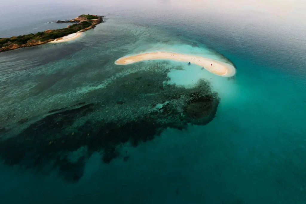 Aerial view of a small Sri Lanka sandbar surrounded by clear turquoise water and coral reefs.