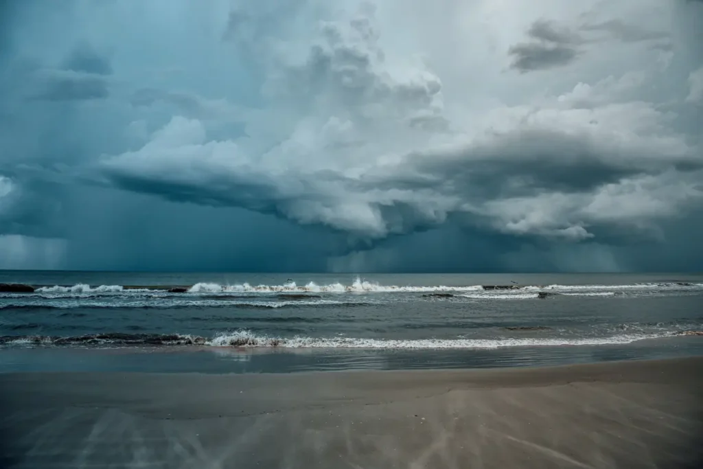 Dark storm clouds gathering over a beach with waves rolling ashore.