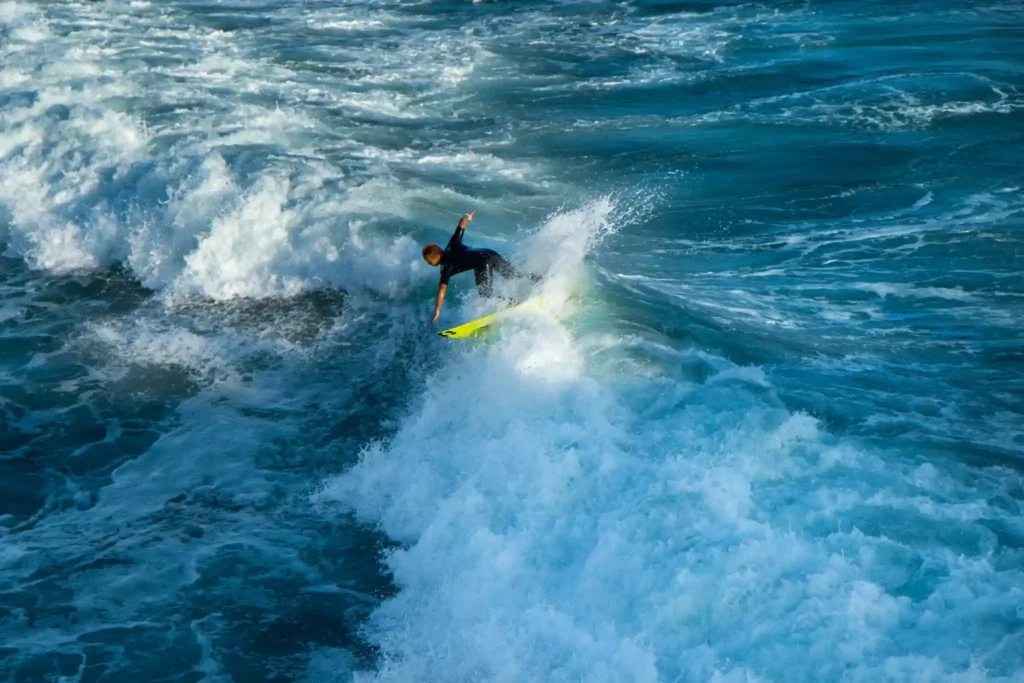 Surfer carving through a powerful ocean wave with whitewater spray.