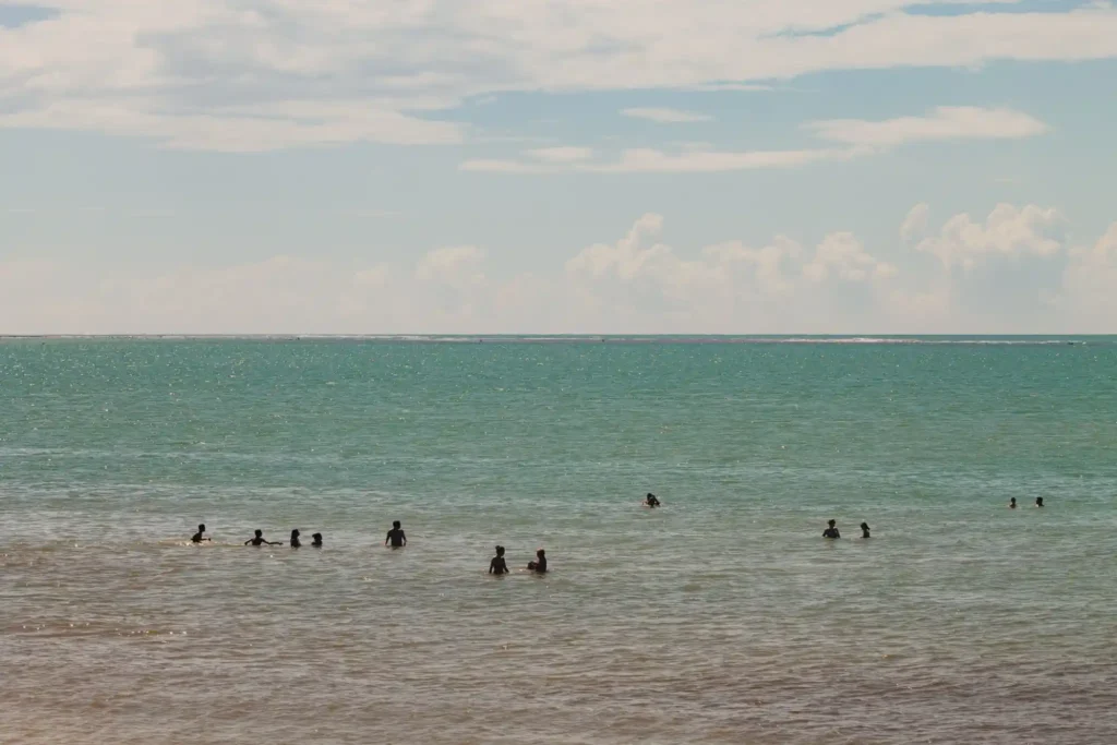 People swimming in shallow beach water.