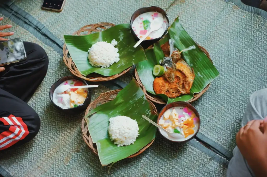 Traditional meal with rice, fish, and dessert served on banana leaves.