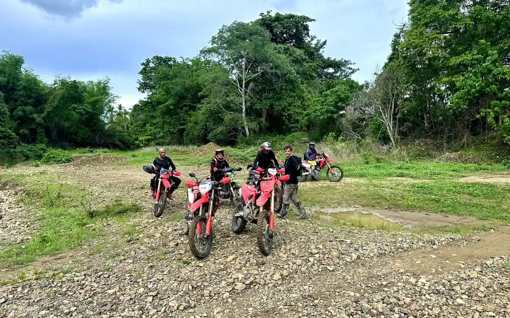 Riders on an off-road motorcycle tour in El Nido crossing rocky terrain.