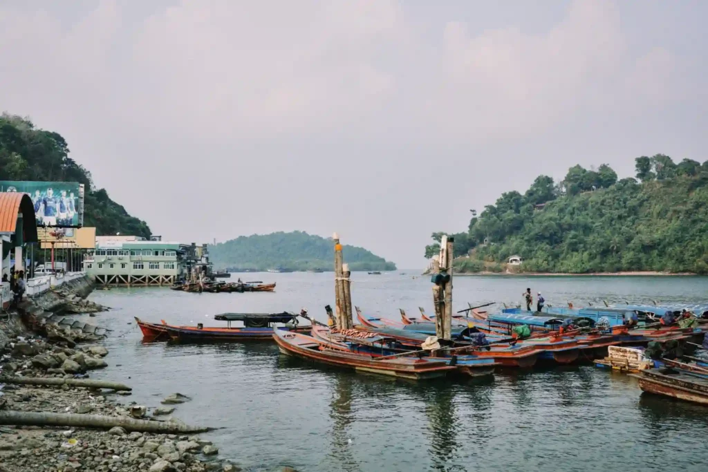 Long-tail boats docked at a quiet coastal harbor.