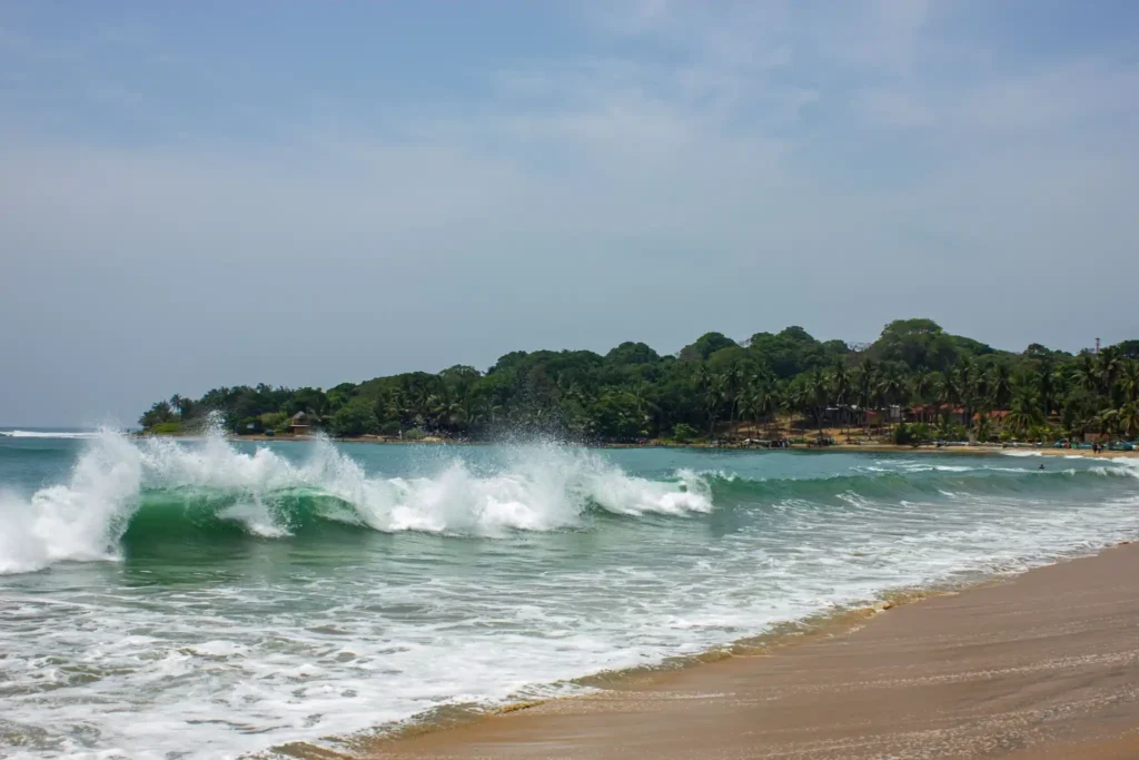 Waves crashing along the sandy shoreline at Mirissa Beach, Sri Lanka.