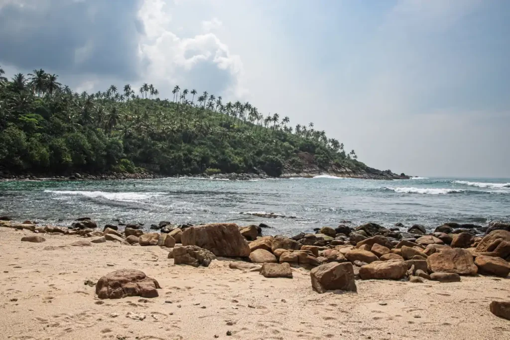 Rocky shoreline at Mirissa Beach with tropical coastline 