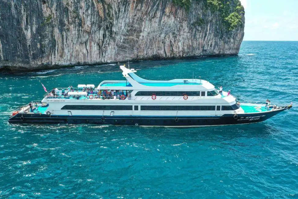 Big boat tour near Phi Phi Island limestone cliffs