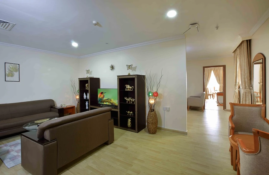 Al Seef Hotel in Sharjah featuring a spacious suite with comfortable sofas, elegant furnishings, decorative shelving and a separate bedroom.