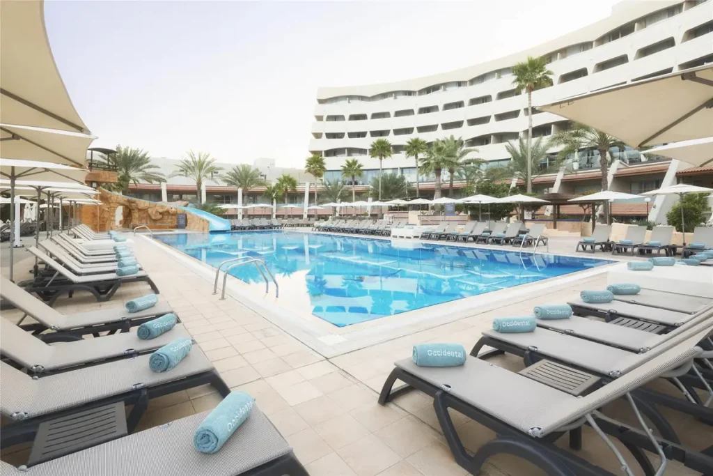 Swimming pool and sun loungers at Occidental Sharjah Grand beachfront hotel.